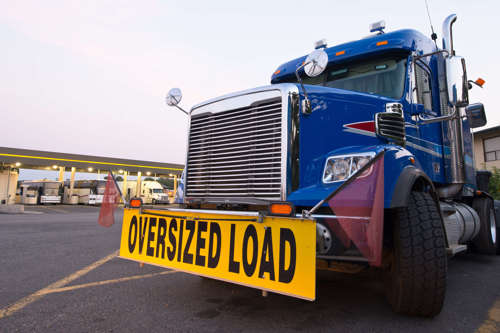 Large truck with oversized load banner on the front